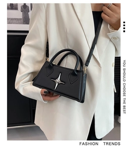 Detail of minimalist black square bag featuring a silver star buckle and hand strap