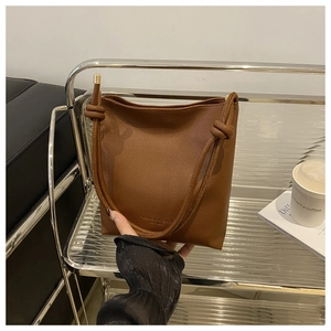 Detailed view of caramel brown lychee leather texture and knot shoulder strap detail
