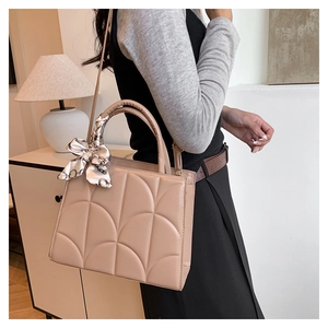 Detail view of khaki tote bag with scalloped quilting and chic scarf wrap on the handle