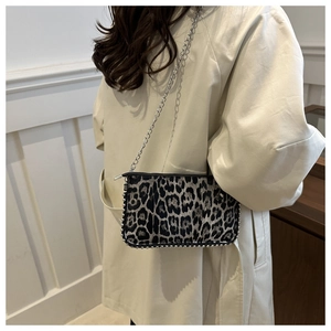 Close-up of leopard print shoulder bag with silver studs on a beige coat outfit