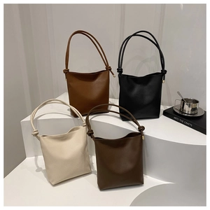 Close-up of minimalist leather crossbody bags in four colors on a white display stand