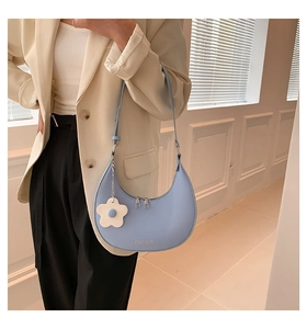 Close-up of light blue crescent hobo bag with floral charm and silver metal zipper