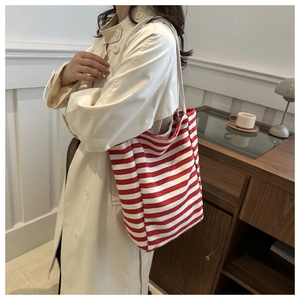 Gros plan du sac fourre-tout en toile à rayures rouges et blanches avec trench-coat