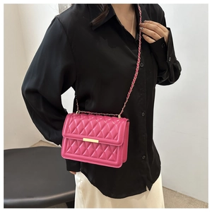Detail of rose pink quilted crossbody bag with gold buckle and metal chain strap