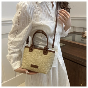 Détail d'un sac en paille tissé main avec poignées en cuir marron et longue bandoulière