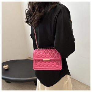 Detail of rose pink quilted crossbody bag with golden chain strap and metallic lock
