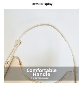Detail view of cream shoulder bag featuring gold zipper and adjustable metal side buckles