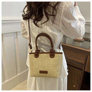 Détail du sac en paille avec poignées en cuir marron et bandoulière réglable