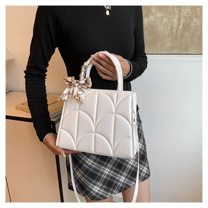 Close-up of white quilted tote bag with decorative silk scarf and chain handle detail