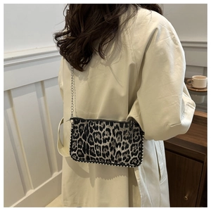 Detail of leopard print shoulder bag with metal studs worn over a beige trench coat