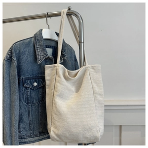 Détail du motif à chevrons du cabas en toile beige suspendu avec veste en jean