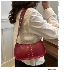Détail d'un sac porté épaule en cuir rouge avec rivets argentés et finition vintage
