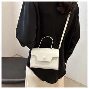 Borsa a tracolla bianca minimalista in pelle con patta indossata da una modella