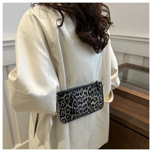 Close-up of leopard print crossbody bag with silver rivets and metal chain strap