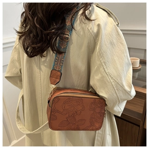 Detail of vintage brown embossed square bag with floral patterns and ethnic wide strap