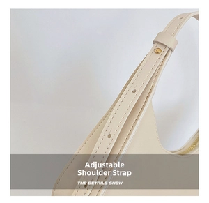 Detail of off-white leather shoulder bag showing adjustable strap with gold metal rivets