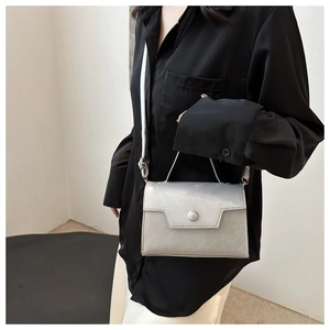 Borsa a tracolla argento metallizzato indossata da modella con gonna bianca