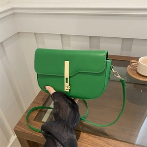 Retro green saddle bag with gold metal buckle shown in a lifestyle afternoon tea setting