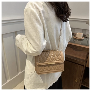 Khaki quilted chain crossbody bag shown on a model in a minimalist indoor setting