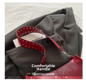 Détail du sac en cuir rouge avec rivets argentés sur la bandoulière et boucle métal