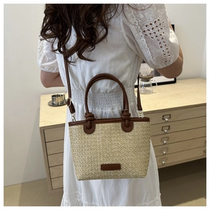 Détail d'un sac cabas en paille avec bordure en cuir marron et robe en dentelle blanche