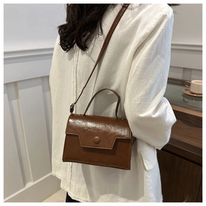 Borsa a tracolla marrone in similpelle con fibbia rotonda in ambiente lifestyle