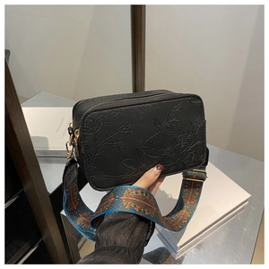 Fashionable black leather crossbody bag with rose floral embossing and colorful wide strap