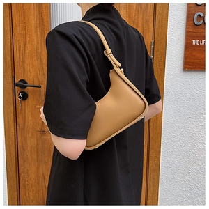 Detail of adjustable camel faux leather strap with metallic buckle on underarm bag