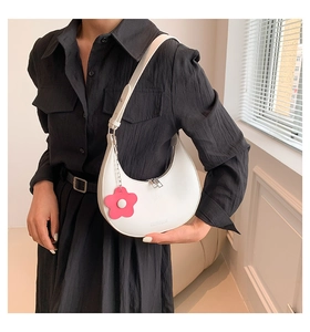 Close-up of a white crescent hobo bag with fashion embossing and pink floral charm