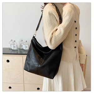 Close-up of black lychee grain leather hobo bag with ethnic style woven wide shoulder strap