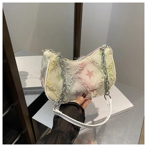 Detail view of denim underarm bag featuring colorful star patterns and frayed fringe edges