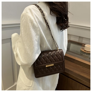 Detailed view of dark brown quilted leather shoulder bag with golden chain strap on model
