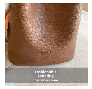 Detailed macro view of caramel lychee grain leather bucket bag with embossed logo