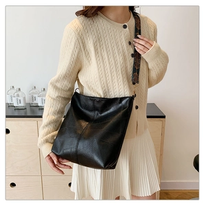 Detail of black pebbled leather bucket bag featuring ethnic patterned wide shoulder strap