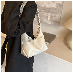 Detail of cream half-moon underarm bag with decorative woven chain strap on shoulder