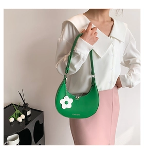 Detail of green crescent shoulder bag with white flower charm and smooth PU texture