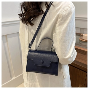 Dettaglio di una borsa a tracolla blu scuro testurizzata con chiusura ad anello in foto