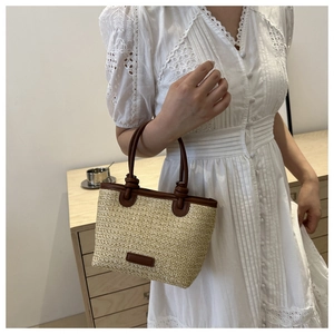 Détail du sac à main d'été en paille avec anses rondes en cuir marron et bordure