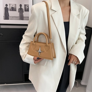 Detail of camel leather crossbody bag with silver star clasp and elegant top handle