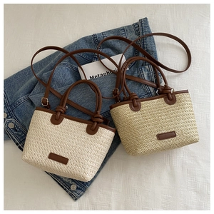 Détail d'un sac à main en paille tressée avec poignées en cuir et bandoulière réglable