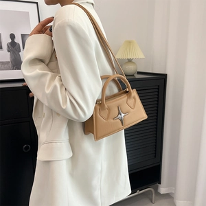 Detail of apricot square crossbody bag featuring a silver star emblem and leather handle
