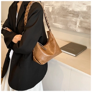 Close-up of vintage brown underarm bag featuring a textured finish and woven chain strap