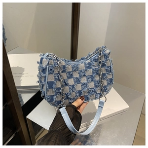 Detail of blue checkerboard denim crescent bag with frayed edges and silver chain strap