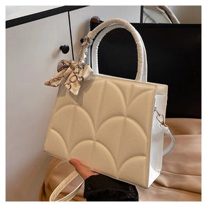 Detail of white quilted patent leather tote bag with elegant printed scarf on handle