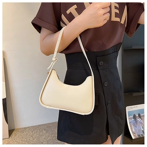 Detail of a minimalist off-white leather baguette bag with adjustable strap and gold zipper