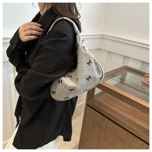 Quilted white hobo bag with black bow prints worn on shoulder in home setting
