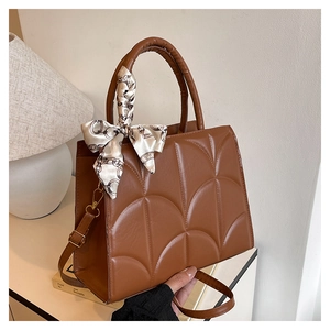Detail of caramel quilted tote bag with a decorative black and white patterned silk scarf