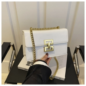 Detail of white leather shoulder bag featuring a large golden geometric metal buckle