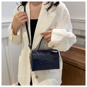 Dettaglio borsa a mano in pelle blu navy abbinata a un blazer in tweed bianco di classe