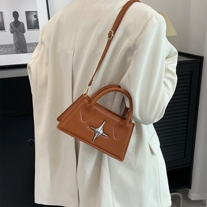 Detailed view of caramel leather crossbody bag with silver star logo and sleek top handle